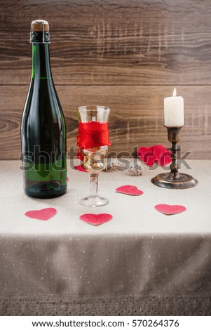 Valentine's Day. wine, candles, small heart on the wooden background