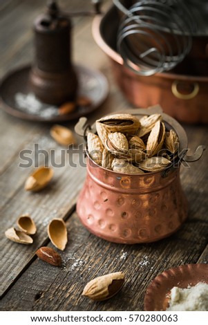 Almonds in the shell. Copper vintage kitchenware, rustic style. Copy space. Vintage crockery. The mysterious atmosphere
