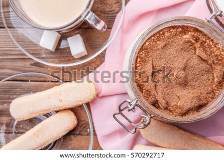 Tiramisu, savoiardi biscuits with mug of coffee on brown wooden table
