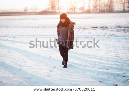 Woman shooting outside in the countryside in the winter on sunset. Color toned image. woman is looking for the best view.Young woman is walking in the meadow.