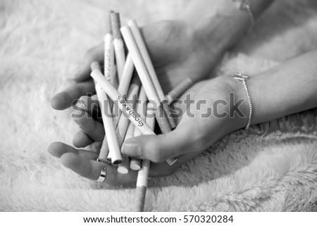 Pile of cigarettes with written messages in girls hands 