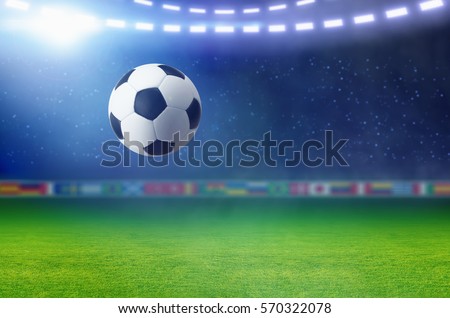 Sports background - soccer ball, bright spotlight illuminates green football field.