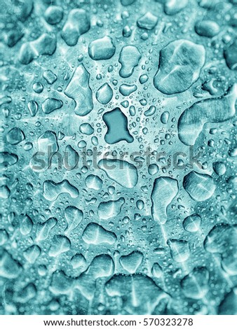 Closeup of a set of raindrops in different shapes on a metal surface, textured in turquoise tones with blurry edges and irregular stains and a darker detailed drop.