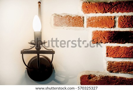 Part of the brick wall of red brick with white seams.Lamp stylized old candle in the chandelier.