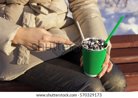 Hot Chocolate with Marshmallows in Paper Cup.Hot Drinks on the Street in Winter. Cup with a Hot Drink in the hands of the Girls. The Street Food. Fast food