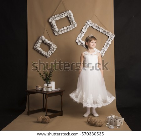 Cute little girl in the white dress posing on a brown background.