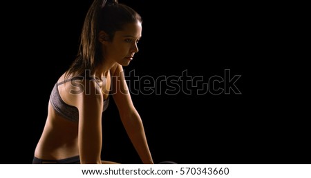 Young Caucasian woman works out on a black background with copy space