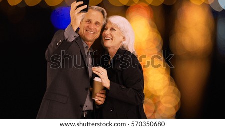 Elderly couple using smartphone to take selfies with the view