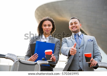 Young business people drinking coffee, standing near bicycle in the city. Thumb up