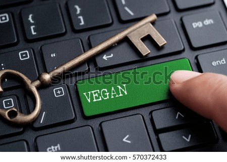 Closed up finger on keyboard with word VEGAN