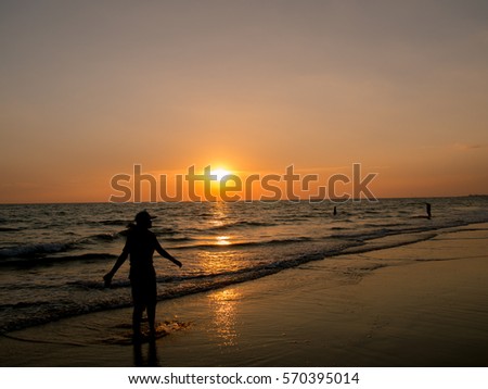 Silhouetted woman standing in a water on the sea at sunset,woman feeling free on sand