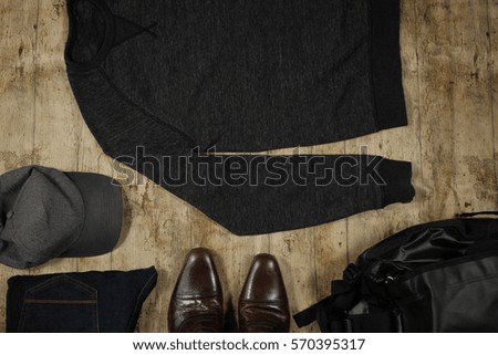 Men's fashion flat lay of a dark sweater, grey cap, leather shoes and a black bag