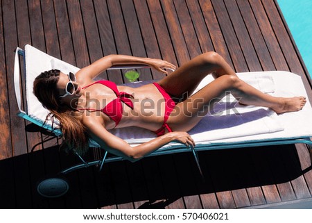 Woman enjoying sunbath on the pool edge on a sunny day