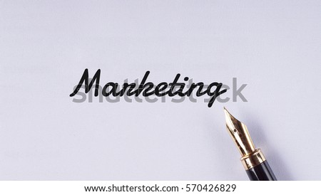 "Marketing" words written on white paper using fountain pen - business and finance concept