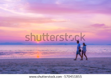 people walking on the beach at sunset over sea background. Blur photo