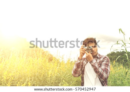 Handsome man take a photo with classic camera,Hipster man take photos in nature ,landscape,macro picture .He is traveler, vintage tone,old film effect