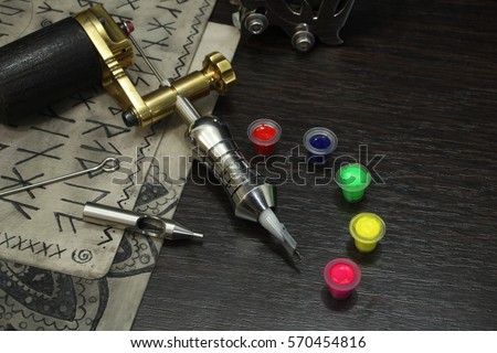 Tattoo machine with ink and sketches on tattoo skins on dark wooden background