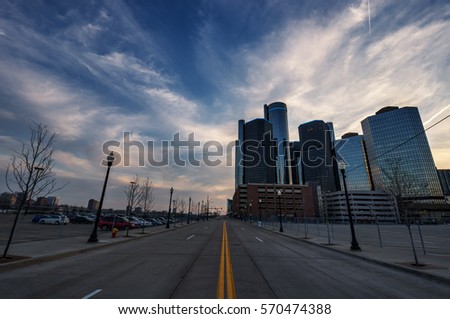 A road leading to a group of tall buildings in the distance with blue skies