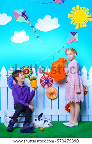 Two happy children play together in spring Easter decorations. Easter Bunny and painted eggs. Kid's fashion. 