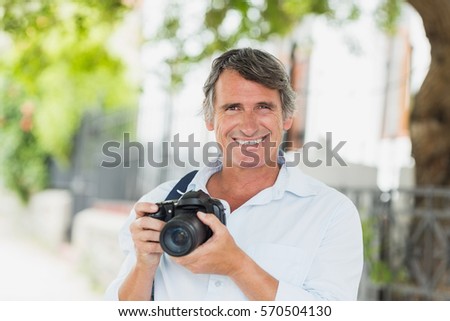 Portrait of happy man with camera in city