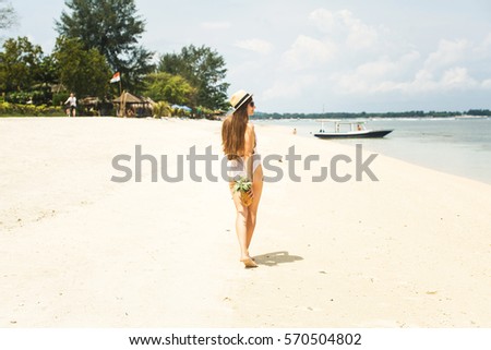 girl in hat holding pineapple on the beach near ocean