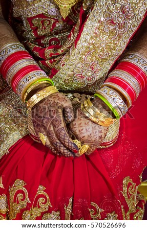 Close up of hands of beautiful Indian bride at a traditional Indian wedding decorated with Heena and gold jewelry. 