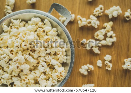 Popcorn in the pan on a wooden table.