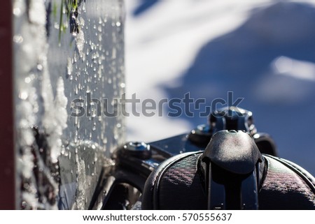 Objects. Detail of snowboard bindings with a dark color, with melted snow and water drops.