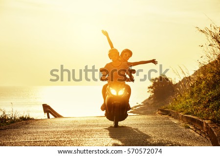 Happy couple traveling on motorcycle on sea coastal road. Travel concept Royalty-Free Stock Photo #570572074