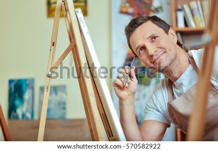 Happy artist dreaming in painting studio.