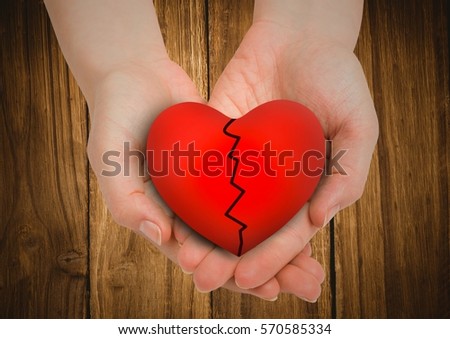 Close-up of broken heart in cupped hands against wooden background