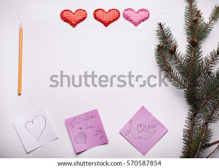 Wooden white background with a branch of pine and three hearts. The concept for Valentine's Day