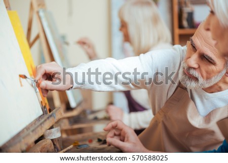 Concentrated man painting with his colleague