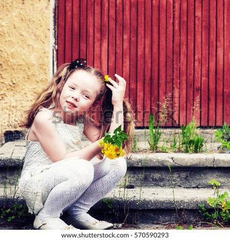 Girl with flowers sitting near the house