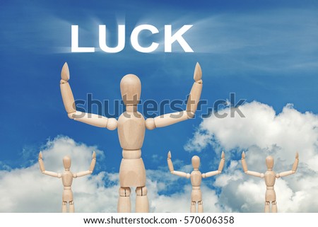 Wooden dummy puppet on sky background with word LUCK. Abstract conceptual image.