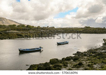 Panoramic landscape picture of two empty wooden boat in the middle of a lake on a cloudy spring afternoon in Ireland.