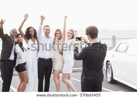 Well dressed people taking pictures next to a limousine on a night out