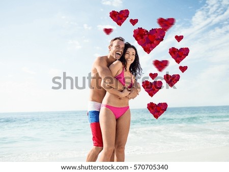 Couple embracing each other on the beach with digitally generated red heart