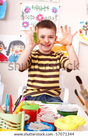 Child with picture and brush in play room. Preschool.