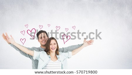 Portrait of couple standing with arms outstretched against digitally generated heart background