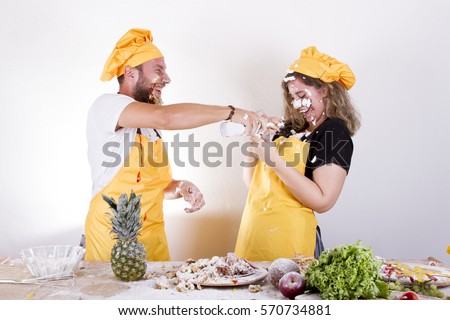 Amusing young couple with flour on faces making funny faces on the kitchen together isolated on white background