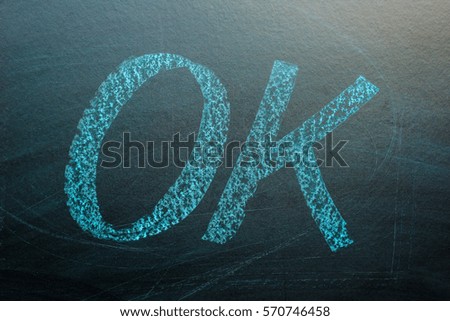 free hand OK text write by blue chalk on black board