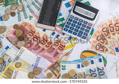 calculator and euro coin lying on euro bills.