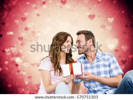 Composite image of romantic couple holding gift box against pink background
