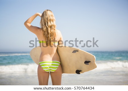 Blonde woman holding surfboard at the beach