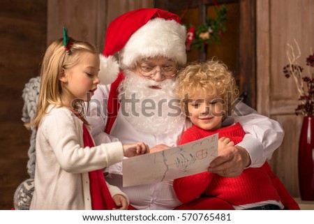 Portrait of happy children showing picture to Santa Claus 