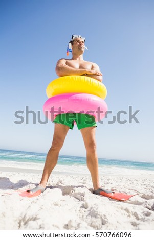 Smiling man posing with rubber ring on the beach