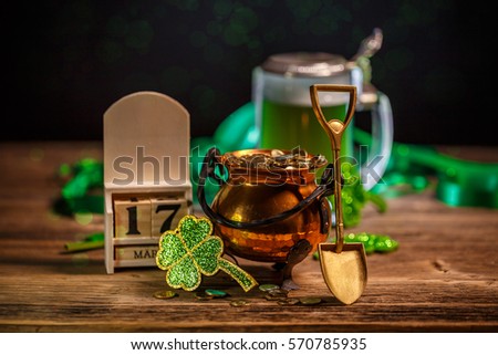 St Patrick's Day concept with pot of gold, shamrock and block calendar on wooden background.