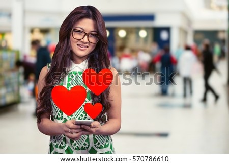 Conceptual image of smiling woman texting on mobile phone with digital generated red hearts
