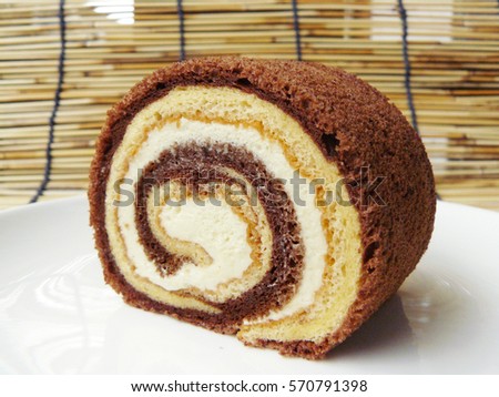 Close up side view of Two tone vanilla and chocolate roll cake in a white plate.